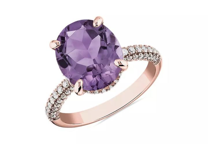 An engagement ring featuring light purple rose de france amethyst oval cut center accented by two rows of pavé diamonds through the rose gold shank